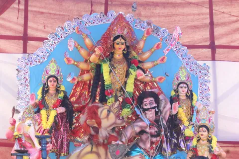 Durga Puja pandal idol with silver lace arch and blue backdrop