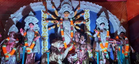 Durga Puja pandal idol in white and silver, blue backdrop