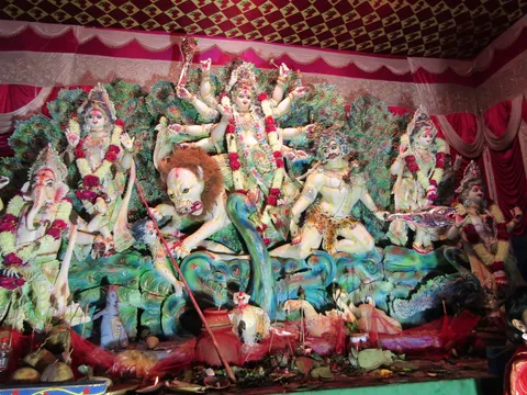 Durga Puja pandal idol with peacock-feather backdrop
