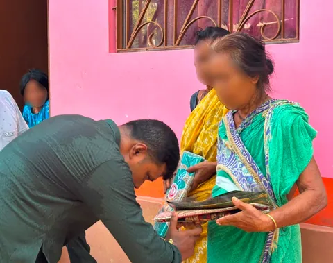 Volunteer bowing to an elderly woman during a Durga Puja clothes distribution