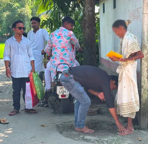 Volunteers distributing clothes to an elderly woman during Durga Puja