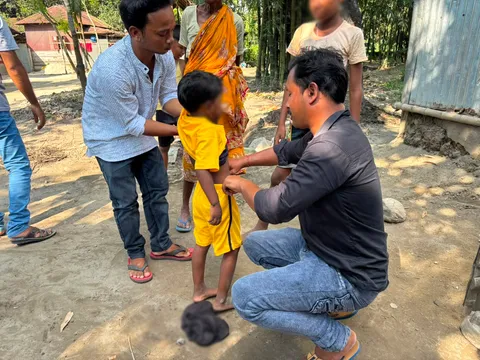 Volunteer fitting new clothes on a child during Durga Puja