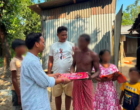 Volunteer distributing clothes to a family during Durga Puja