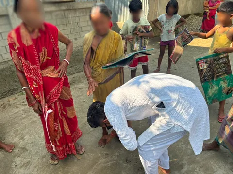 Volunteer bowing to an elderly woman during a Durga Puja clothes distribution