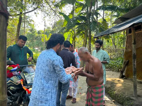 Volunteer handing clothes to an elderly man during Durga Puja