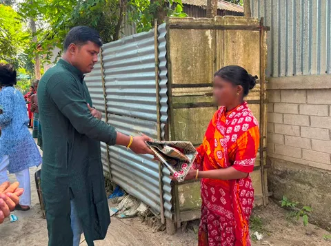 Volunteer handing folded clothes to a woman during Durga Puja