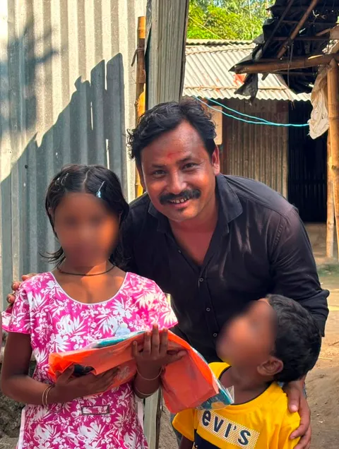 Volunteer with two children during a Durga Puja clothes distribution